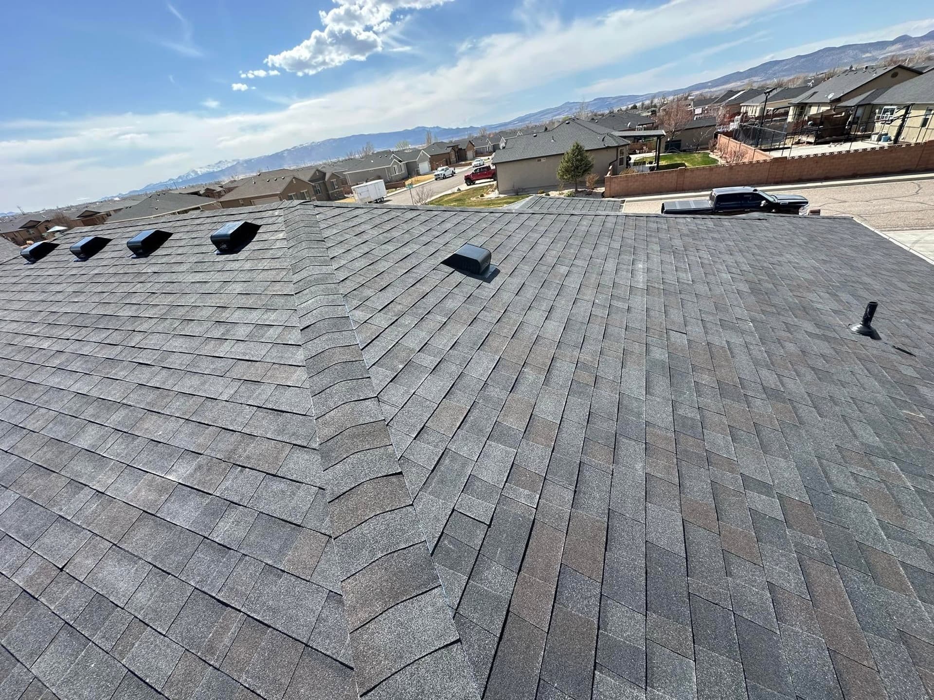New charcoal architectural shingle roof on a Cedar City home with snow-capped mountains behind it