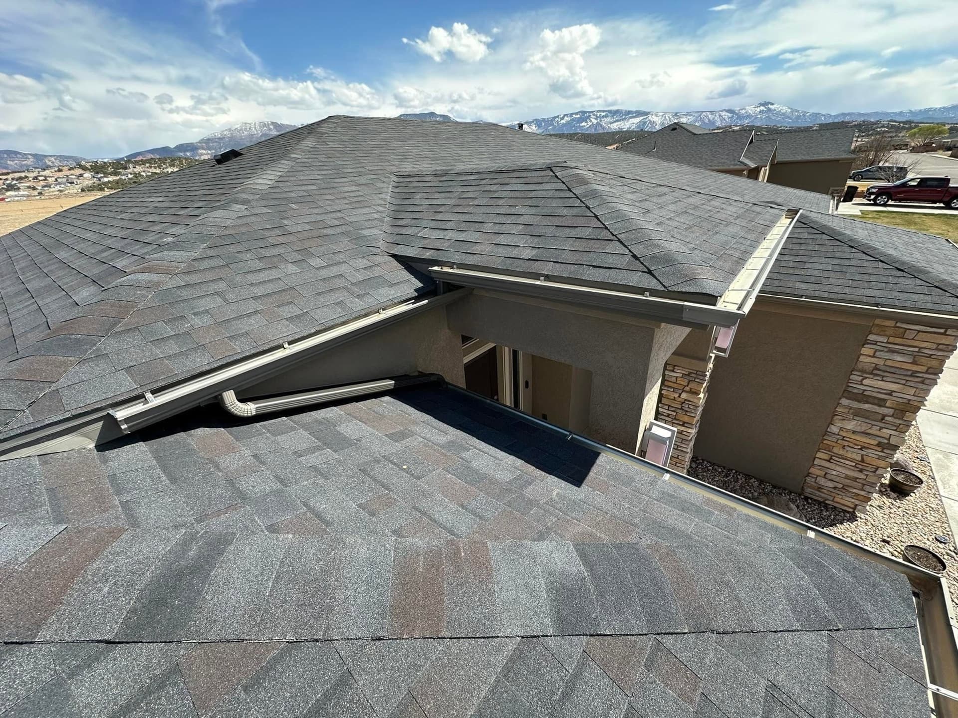 Finished charcoal shingle roof on an upscale Cedar City home framed by snow-capped mountains